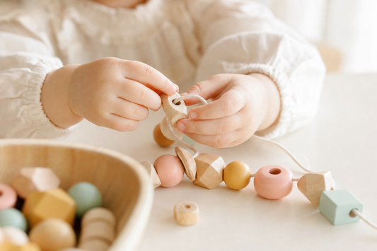 Enfant qui joue avec des perles en bois pour développer la motricité fine